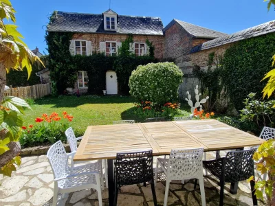 Espace jardin privatif fleuri et engazonné avec terrasse équipée d'une table jardin et d'un barbecue